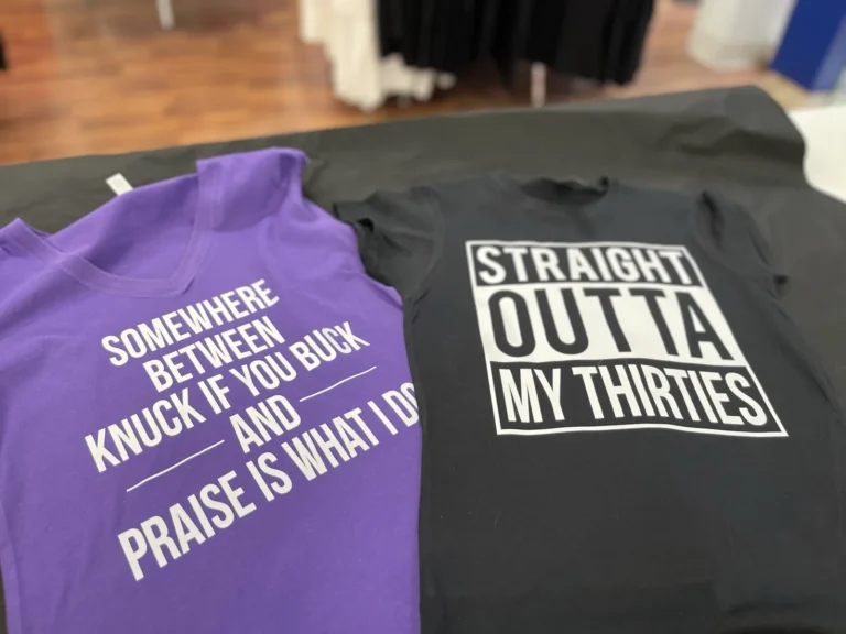 Purple and black shirts with bold white slogan designs