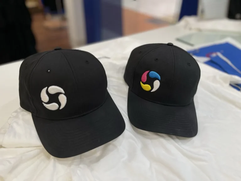 Two black caps with white and multicolor swirl logos